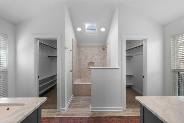 bathroom with wood-type flooring, vanity, and vaulted ceiling with skylight