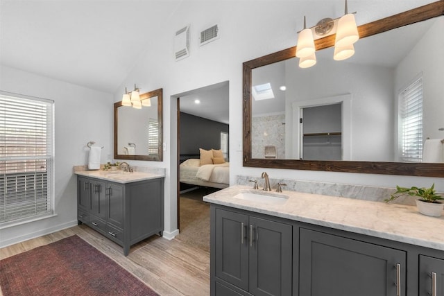 bathroom with hardwood / wood-style floors, vanity, and vaulted ceiling with skylight