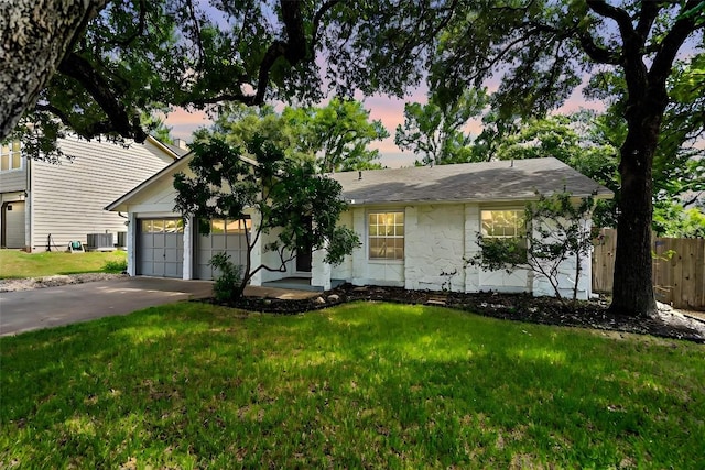 single story home featuring cooling unit, a garage, and a yard