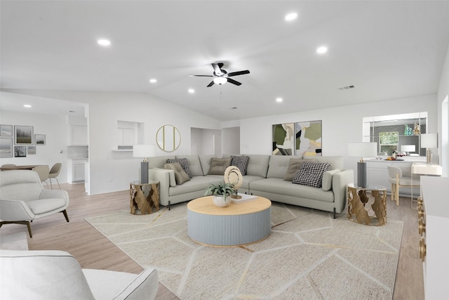 living room with ceiling fan, light hardwood / wood-style flooring, and vaulted ceiling