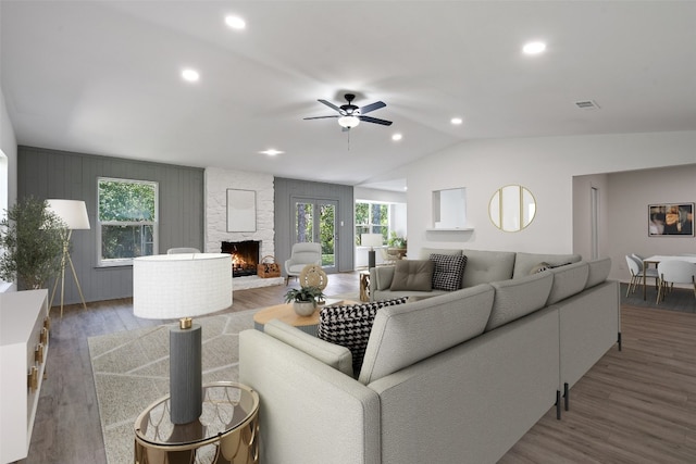 living room featuring a fireplace, hardwood / wood-style flooring, vaulted ceiling, and ceiling fan