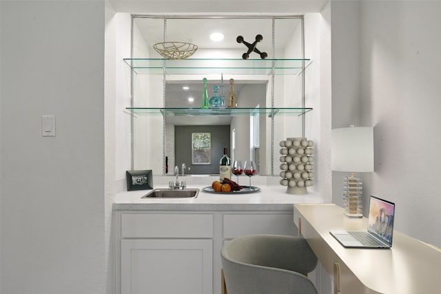 bar with white cabinetry and sink