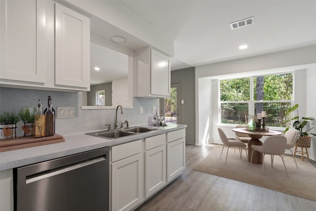 kitchen with white cabinetry, dishwasher, sink, backsplash, and light hardwood / wood-style floors