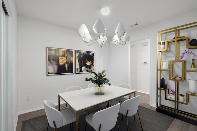 dining area with dark hardwood / wood-style flooring and an inviting chandelier