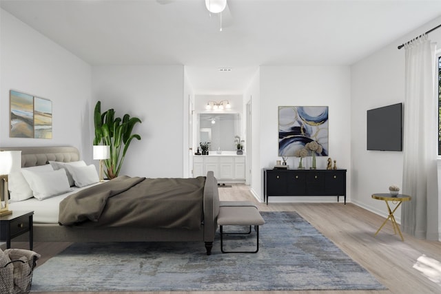 bedroom with ensuite bath, ceiling fan, and light wood-type flooring