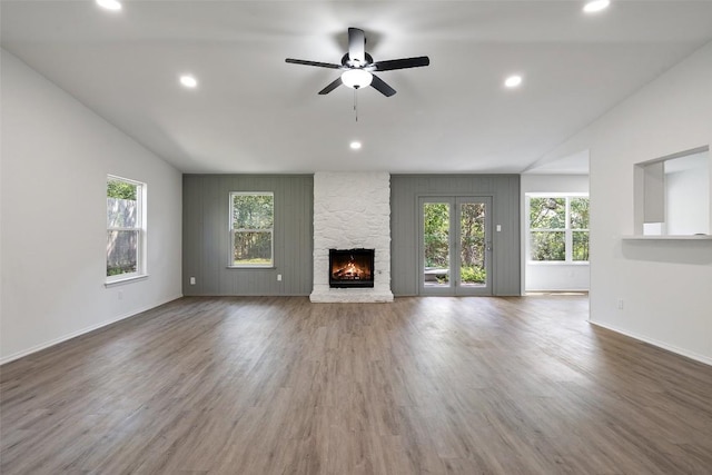 unfurnished living room with a stone fireplace, ceiling fan, lofted ceiling, and hardwood / wood-style flooring