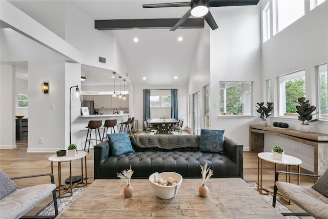 living room with beamed ceiling, ceiling fan, high vaulted ceiling, and light hardwood / wood-style flooring