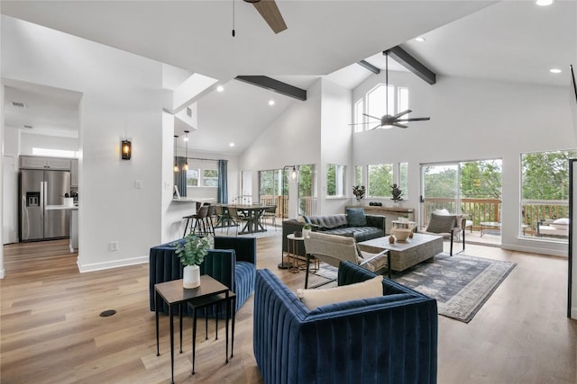 living room with beamed ceiling, a wealth of natural light, light wood-type flooring, and ceiling fan