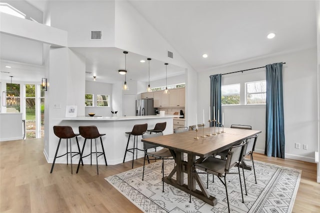 dining space featuring high vaulted ceiling and light wood-type flooring