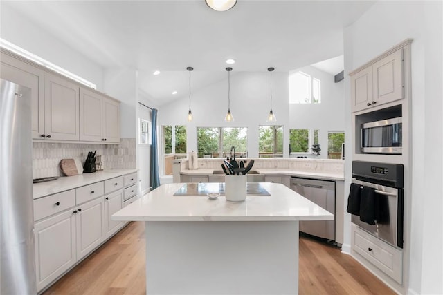 210 Finn St, Austin, TX 78734 - kitchen with stainless steel appliances, decorative backsplash, a kitchen island, light countertops, and light wood-type flooring