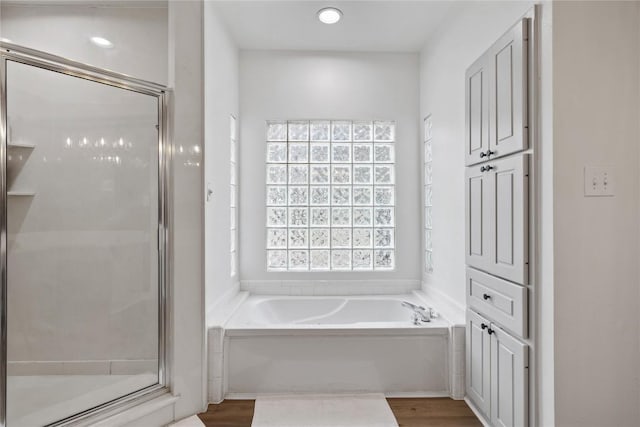 bathroom featuring wood-type flooring and plus walk in shower