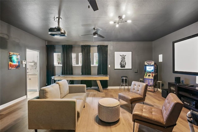 home theater room featuring a textured ceiling, light hardwood / wood-style floors, and a notable chandelier