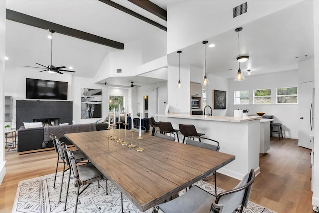 210 Finn St, Austin, TX 78734 - dining room with ceiling fan, a fireplace, light wood-style floors, beamed ceiling, and high vaulted ceiling
