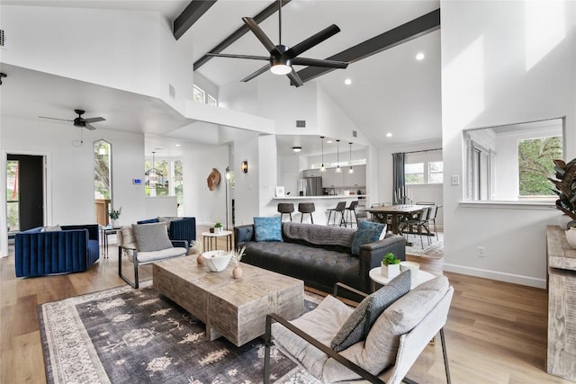 living room with beamed ceiling, light hardwood / wood-style flooring, high vaulted ceiling, and ceiling fan