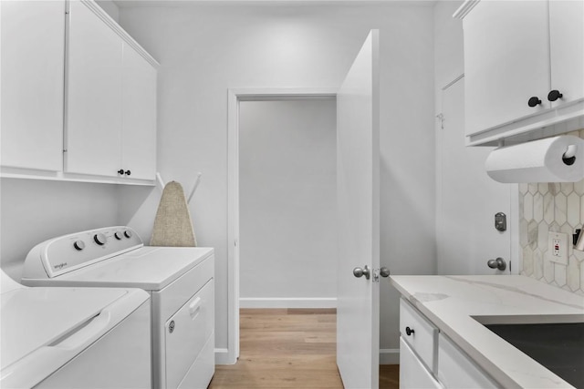 laundry area with cabinets, light hardwood / wood-style floors, and washer and dryer