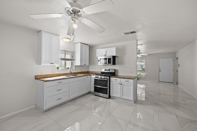 kitchen with white cabinets, appliances with stainless steel finishes, ceiling fan, and sink