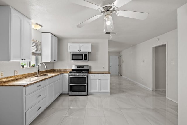 kitchen featuring light stone countertops, white cabinetry, sink, ceiling fan, and stainless steel appliances