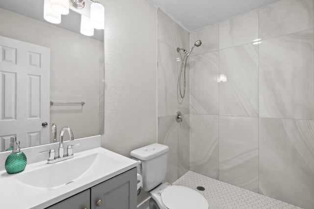 bathroom with vanity, toilet, and a tile shower