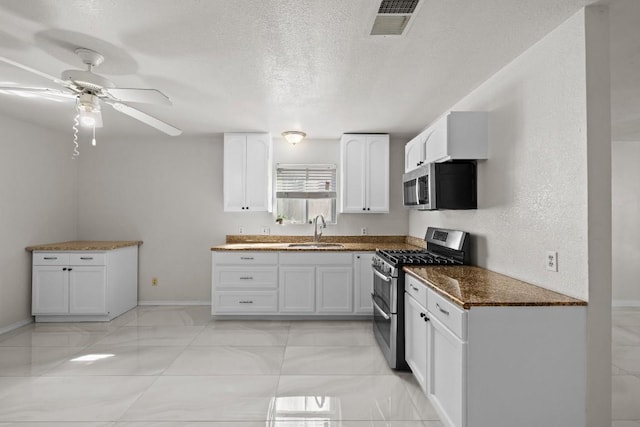 kitchen with appliances with stainless steel finishes, a textured ceiling, ceiling fan, sink, and white cabinetry