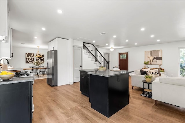 kitchen featuring light stone countertops, stainless steel refrigerator with ice dispenser, light hardwood / wood-style flooring, white cabinets, and a kitchen island