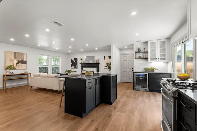 kitchen featuring a breakfast bar, white cabinets, stainless steel stove, a kitchen island, and beverage cooler