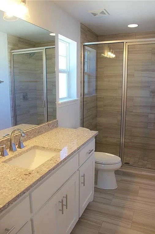 bathroom with tile patterned flooring, vanity, toilet, and a shower with door