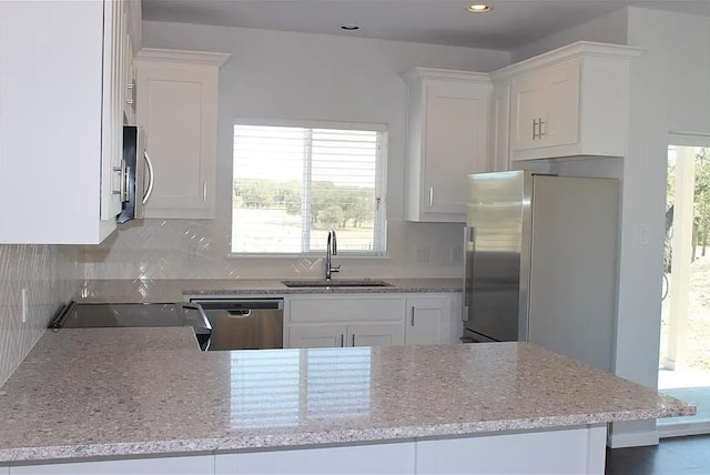 kitchen with white cabinets, appliances with stainless steel finishes, kitchen peninsula, and sink