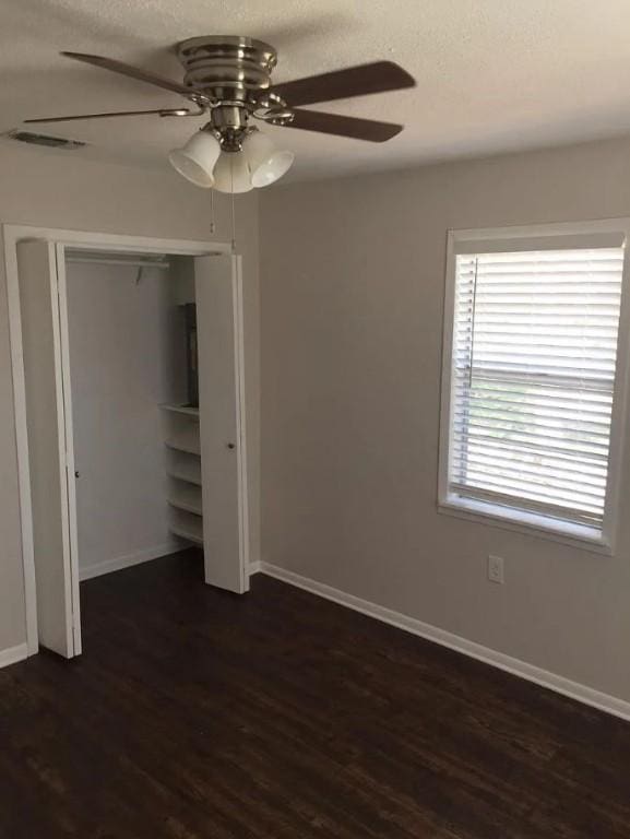 unfurnished bedroom featuring ceiling fan, dark wood-type flooring, and a closet