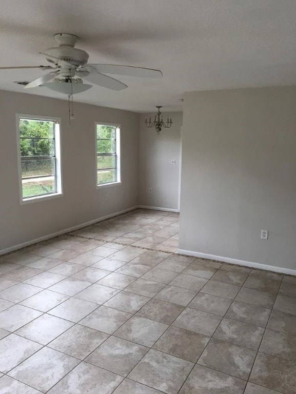 empty room with light tile patterned flooring and ceiling fan with notable chandelier