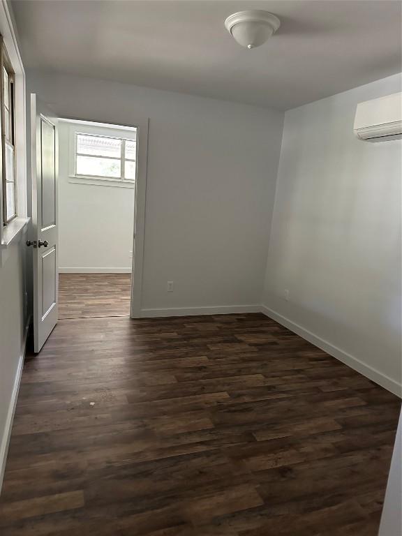 spare room with a wall mounted air conditioner and dark hardwood / wood-style floors