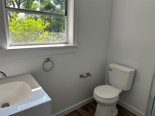 bathroom featuring plenty of natural light, toilet, wood-type flooring, and vanity