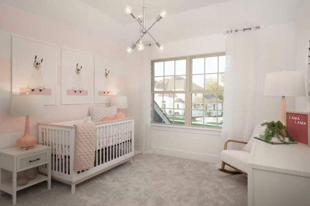 carpeted bedroom with a chandelier and a nursery area