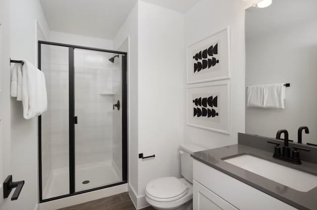 bathroom with hardwood / wood-style floors, vanity, toilet, and an enclosed shower