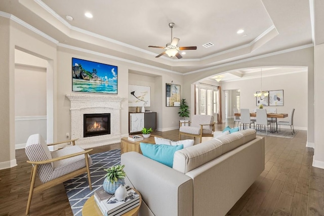 living room featuring dark hardwood / wood-style floors, a raised ceiling, ceiling fan, and ornamental molding