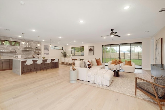 living room featuring ceiling fan, sink, and light hardwood / wood-style flooring