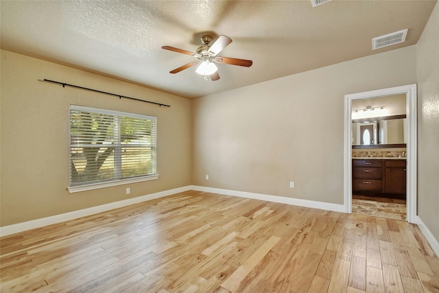 unfurnished room featuring ceiling fan, light hardwood / wood-style flooring, and a textured ceiling