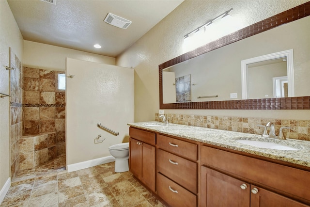 bathroom featuring vanity, a shower, a textured ceiling, and toilet