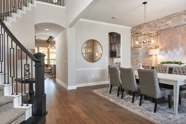 dining area featuring dark hardwood / wood-style flooring, crown molding, and a notable chandelier