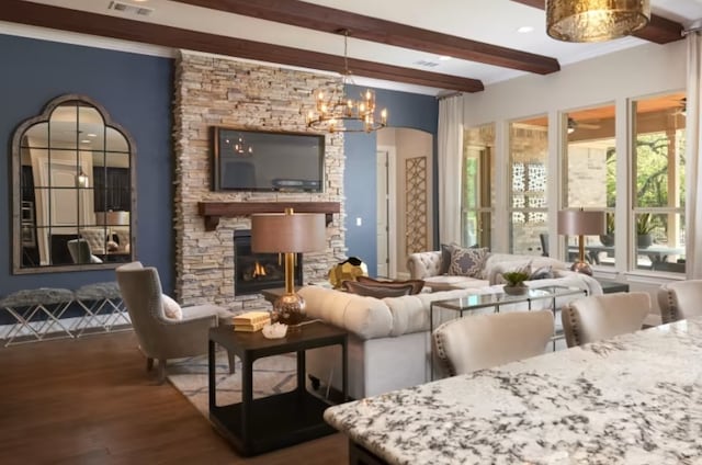 living room with beamed ceiling, dark hardwood / wood-style flooring, ceiling fan with notable chandelier, and a fireplace