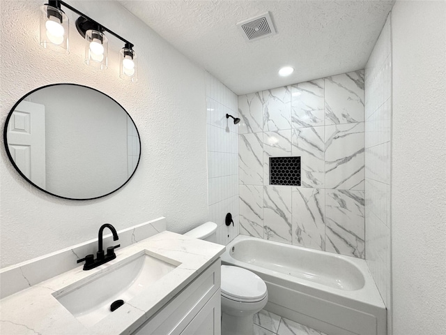 full bathroom with vanity, toilet, a textured ceiling, and tiled shower / bath combo