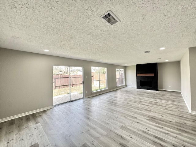 unfurnished living room featuring a fireplace, light wood-type flooring, and a textured ceiling