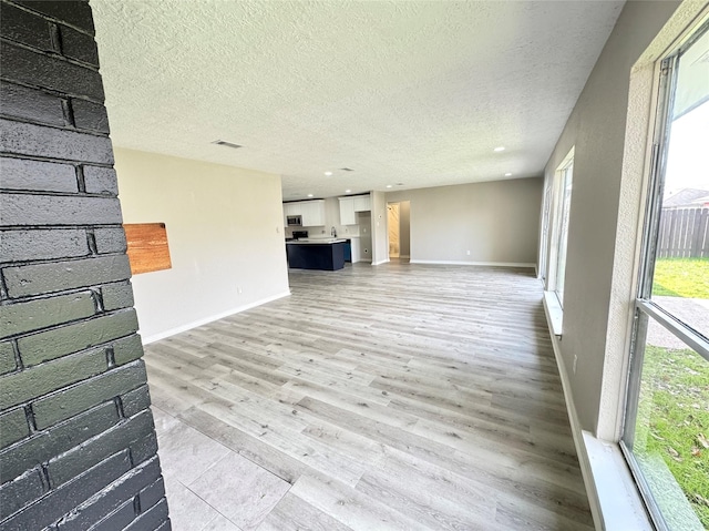 unfurnished living room featuring hardwood / wood-style floors and a textured ceiling