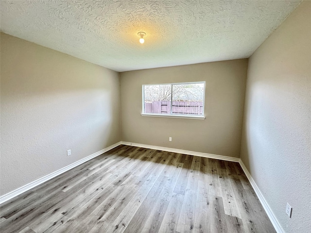 spare room featuring wood-type flooring and a textured ceiling