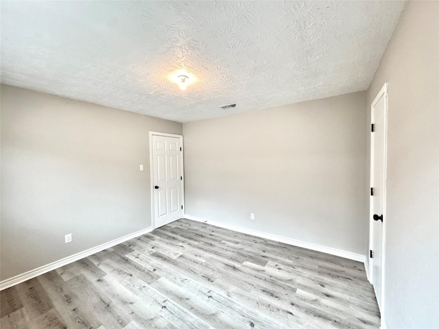 unfurnished room featuring a textured ceiling and light hardwood / wood-style flooring