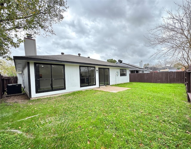 rear view of property featuring central air condition unit and a lawn