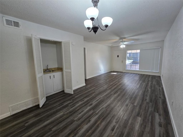 interior space featuring dark hardwood / wood-style flooring, sink, ceiling fan with notable chandelier, and a textured ceiling