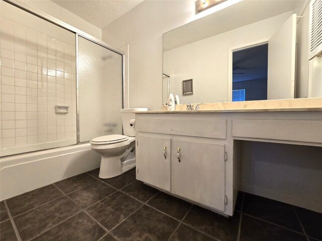 full bathroom with a textured ceiling, shower / bath combination with glass door, tile patterned floors, vanity, and toilet