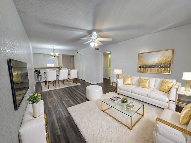 living room featuring ceiling fan with notable chandelier, a textured ceiling, and dark hardwood / wood-style flooring