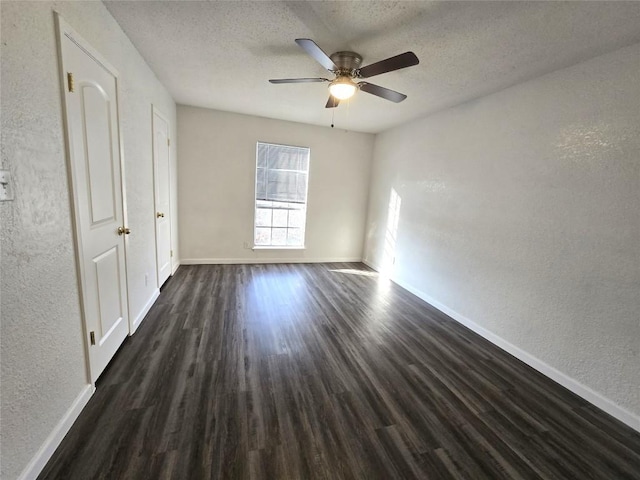 unfurnished room featuring dark wood-type flooring, ceiling fan, and a textured ceiling