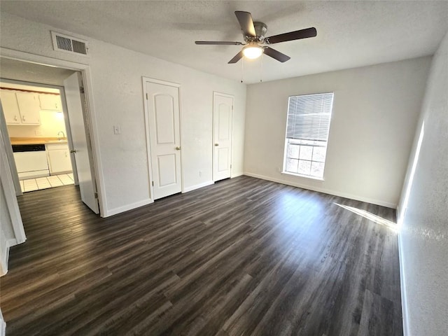 unfurnished bedroom with ceiling fan, dark hardwood / wood-style floors, sink, and a textured ceiling